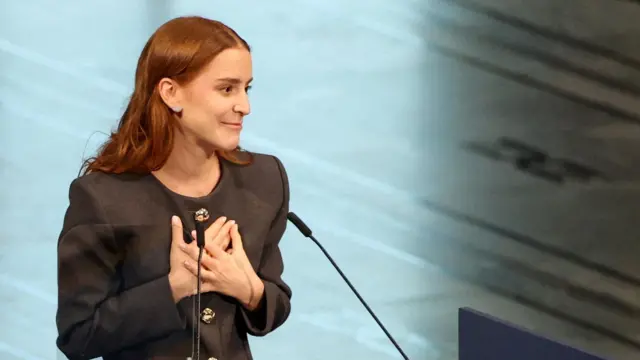 Ana Corina Sosa Machado, daughter of Venezuelan opposition leader Maria Corina Machado, in a grey outfoot, delivers a speech as she receives the Nobel Peace Prize on behalf of her mother, in Oslo, Norway