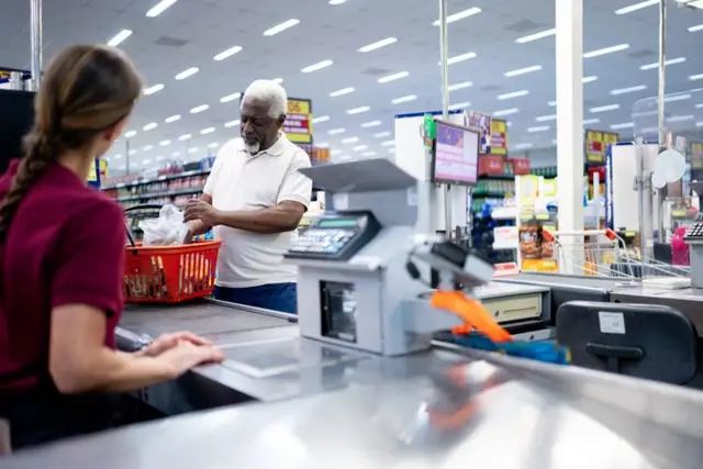 Homem passando em caixa de supermercado