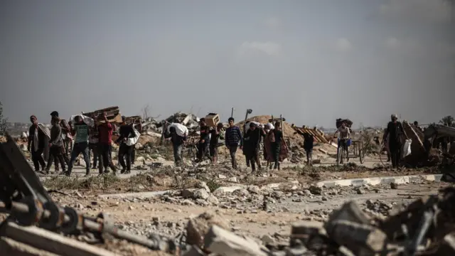 فلسطينيون يحملون مؤناً غذائية إلى خيامهم بعد أن خاطروا بحياتهم للوصول إلى نقطة توزيع مساعدات في منطقة نتساريم، في ظل استمرار الجوع الشديد في مدينة غزة، غزة، 30 سبتمبر/أيلول 2025.