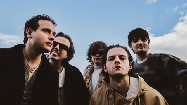 Cinco machos, todos de piel oscura, posan frente a la cámara.