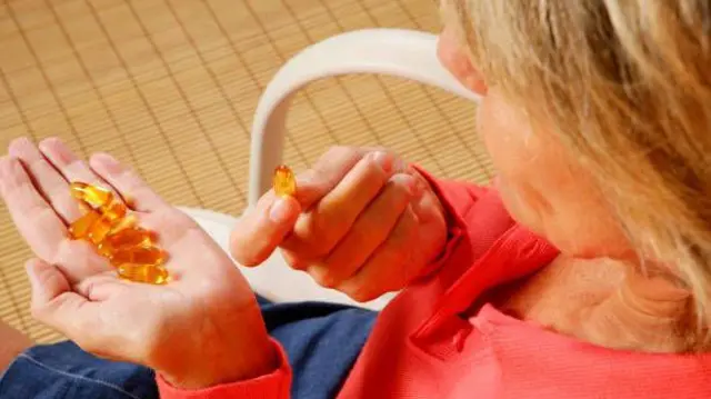 تصویر یک زن که در حال خوردن تابلیتهای ویتامین است.