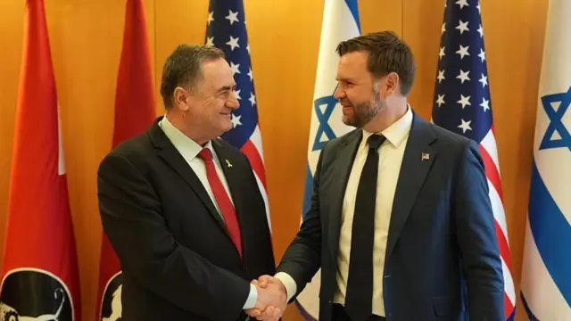 JD vance ve İsrail Katz el sıkışırken. Arkalarında ABD ve İsrail bayrakları var.