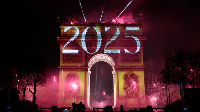 ألعاب نارية وإضاءات على قوس النصر خلال احتفالات رأس السنة الجديدة 2025 في شارع الشانزليزيه في باريس
