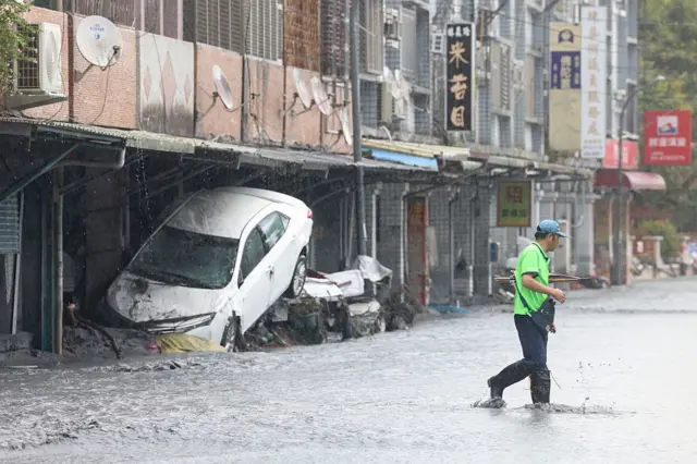 Una calle llena de agua donde se apilan coches arrastrados por la tormenta.