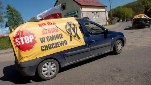 Demonstranci biorą udział w proteście samochodowym, prezentując transparent „Nie dla atomu w gminie Choczewo”, sprzeciwiając się budowie pierwszej w kraju elektrowni jądrowej, w Ciekocinie na północy Polski, 2 maja 2024 roku.