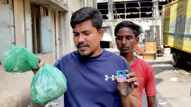 এক হাতে পোড়া মাটি অন্য হাতে ভাইয়ের ছবি দেখাচ্ছেন মোঃ জাকির। পেছনে ফ্যাক্টরির সাবেক কর্মী ইসলাম 