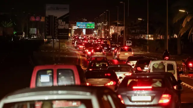 夜の複数車線の道路で長い車列ができている。各車のテールライトが赤く光っている