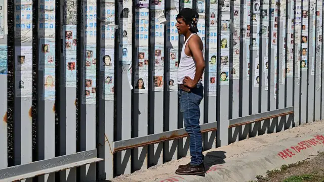 Un hombre con gorra mira el muro que separa México de Estados Unidos.
