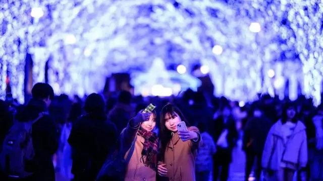 فتيات يلتقطن صورا أمام أضواء الكريسماس في العاصمة اليابانية طوكيو