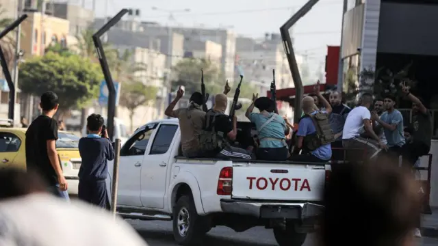 Combatientes de Hamás regresan a la Franja de Gaza en una camioneta con fusiles en el aire                    