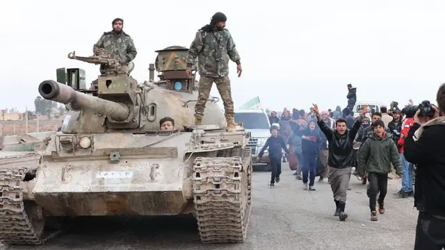 Suriye ordusuna ait bir tank Halep'in doğusunda ilerliyor. Etrafta sevinçli insanlar var. (17 Ocak 2026)