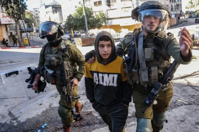 Soldados israelenses detêm um menino durante manifestações9club freebetHebron, 2022. Israel foi acusado9club freebettáticas violentas