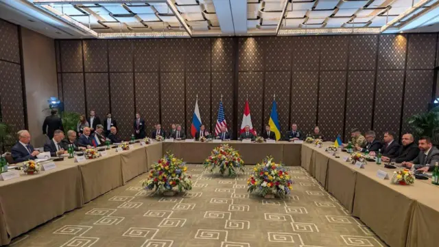 Учасники мирних переговорів у Женеві: ліворуч - російська делегація, праворуч - українська. Посередині - предсатвники США та Швейцарії