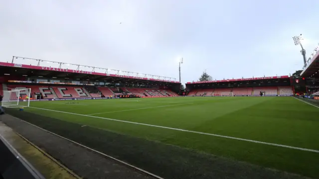 El campo de fútbol del estadio Vitality visto desde una esquina a la derecha de una de las porterías. Las gradas vacías de un solo nivel tienen asientos de plástico rojo, con algunos asientos blancos y negros que forman las letras AFCB.