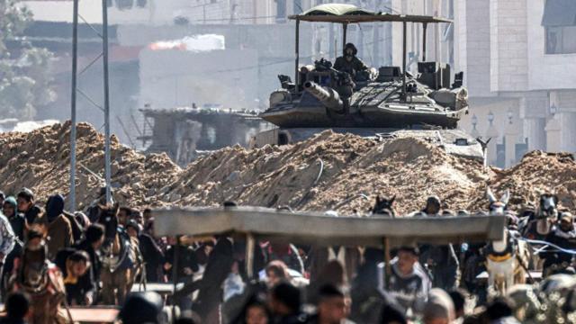 Um tanque israelense é enviado para proteger uma posição enquanto palestinos desalojados fogem de Khan Younis, 30 de janeiro de 2024