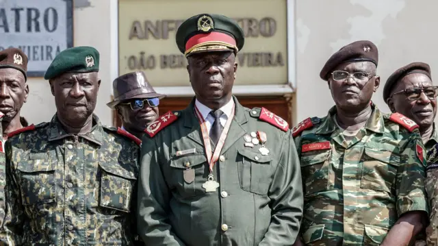 Gen Horta N'Tam ahagaze kugirango afate ifoto, agaragiwe n'abandi basirikare.