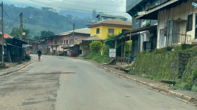 Une rue déserte avec des habitations, des montagnes visibles de loin.