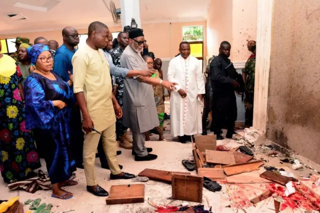 Ondo state govnor Rotimi Akeredolu point to blood on di floor afta one attack by gunmen for St Francis Catholic Church, Owo, Ondo state