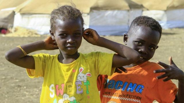Foto tirada em 20 de março de 2024 mostra crianças que fugiram de Cartum e Jazira brincando perto de tendas num acampamento para desalojados no sul do estado de Gadaref, no Sudão