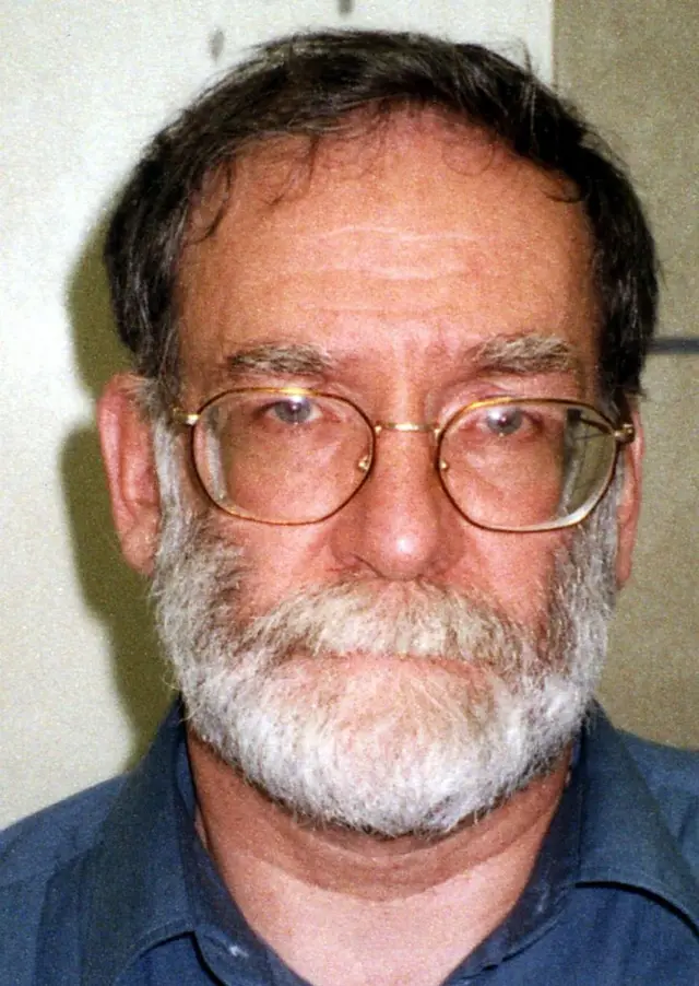 Retrato de Harold Shipman, um homem de pele clara, barba branca e óculos de grau.