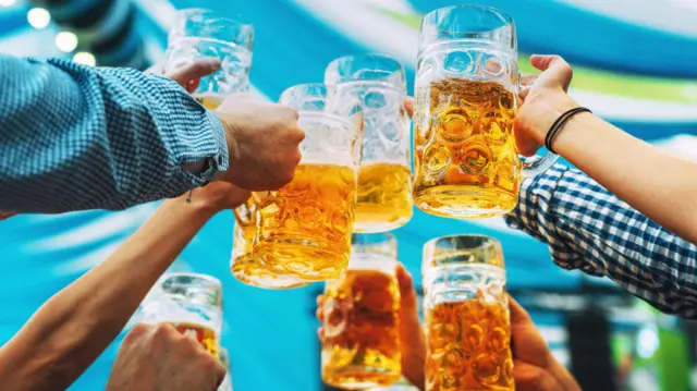 Mãos erguendo copos grandes de cerveja em um brinde