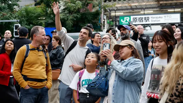 東京JR原宿車站竹下出入口前一群外國遊客在舉起手機拍照(15/10/2025)
