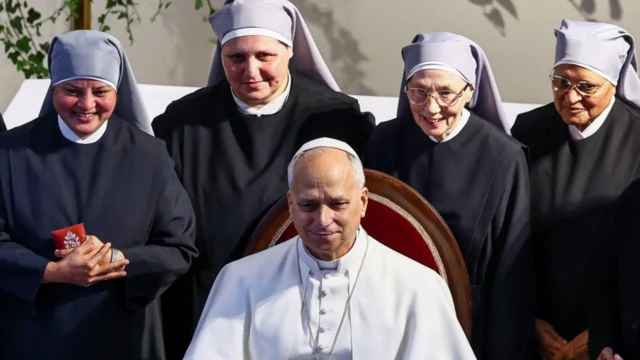 Papa dört rahibenin arasında oturuyor ve poz veriyor