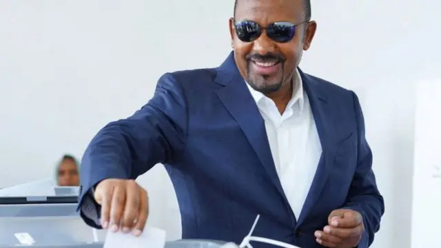 ዐቢይ ጥቁር መነጽር አድርገው የድምጽ መስጫ ካርዳቸውን ሳጥን ውስጥ ሲያስገቡ
