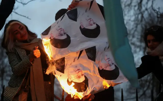 Jovem sorri ao ver fotos de Khamenei queimando