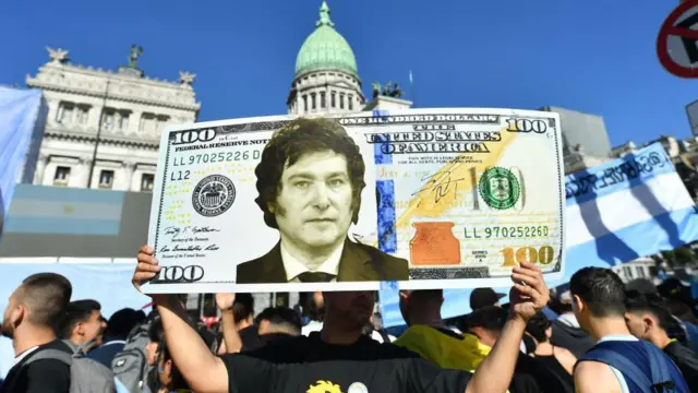 Homem segura cartaz mostrando uma cédulabet fair netdólar com o rostobet fair netMilei 