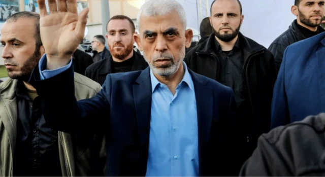 Yahya Sinvar kravatsız takım elbisesiyle halk içinde yürüyor ve birilerini selamlıyor