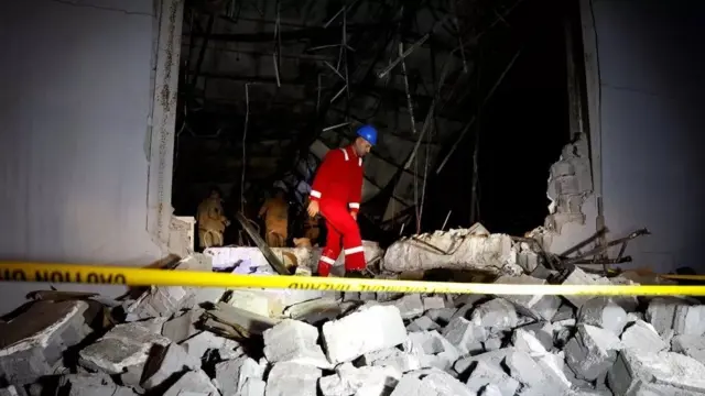 An emergency worker picks through rubble