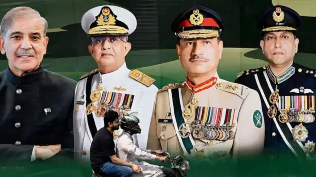 عکس یک عکس بزرگ را در خیابانی در پاکستان نشان می‌دهد که سه ارشدترین مقام نظامی پاکستان در کنار نسخت وزیر شهباز شریف را نشان می‌دهد. یک موترسایکل که دو نفر بر آن حضور دارند از پیش روی این تصویر می‌گذرند.