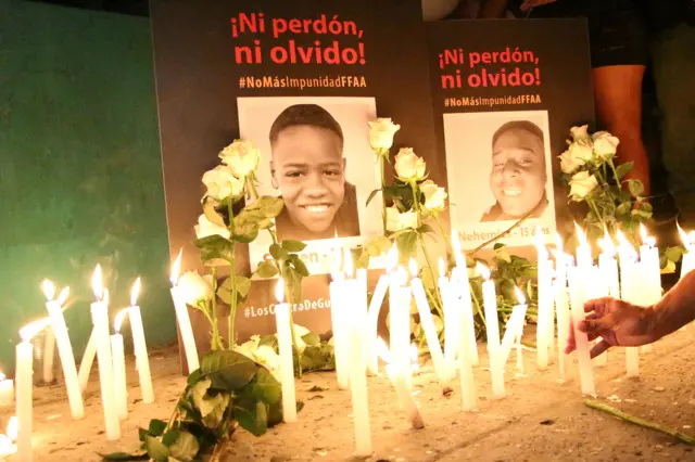 Velas encendidas y flores ante dos retratos de los niños asesinados.