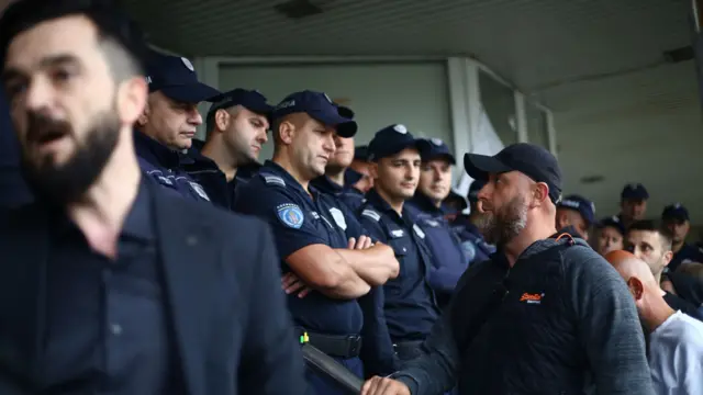 Muškarac u plavoj majici gleda u policajca napolju