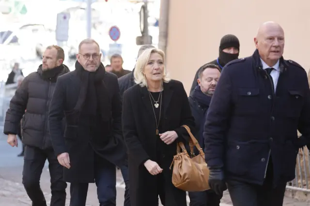 Ле Пен и сопровождающие. Все одеты в темное.