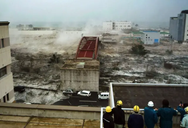 Tsunami menerjang kendaraan dan rumah di sebuah jembatan di kota Sendai di prefektur Miyagi.