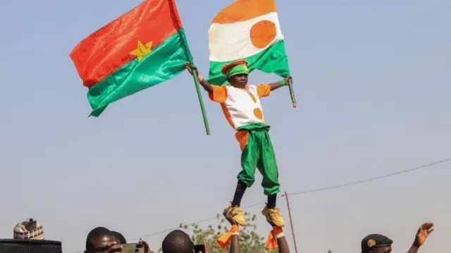 Wani mutum rike da karamin yaro ɗauke da tutar Burkina Faso da ta Nijar.
