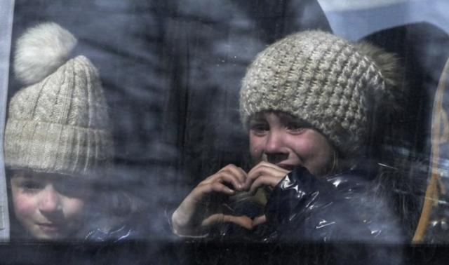 Menina faz coração com as mãos enquanto civis são evacuados da cidade ucraniana de Mariupol, em 24 de março de 2022