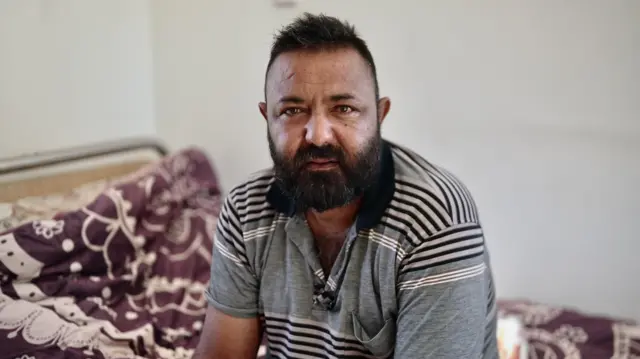 Muškarac s tamnom kosom i bradom gleda u kameru