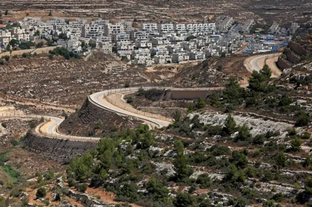 A serpentine road extends between the Jewish settlement of Givat Zeev (background) and Palestinian villages near the Israeli-occupied West Bank city of Ramallah, on September 8, 2023.