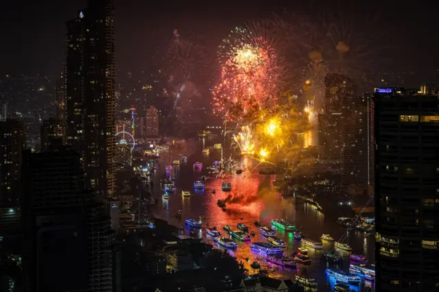 Fireworks over the Chao Phraya river in Bangkok, Thailand, lighting up the skyline and boats