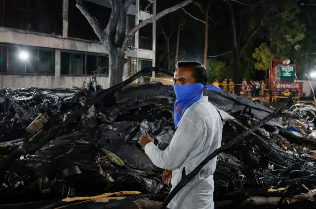 شخص يقف بجوار حطام الطائرة المتفحم