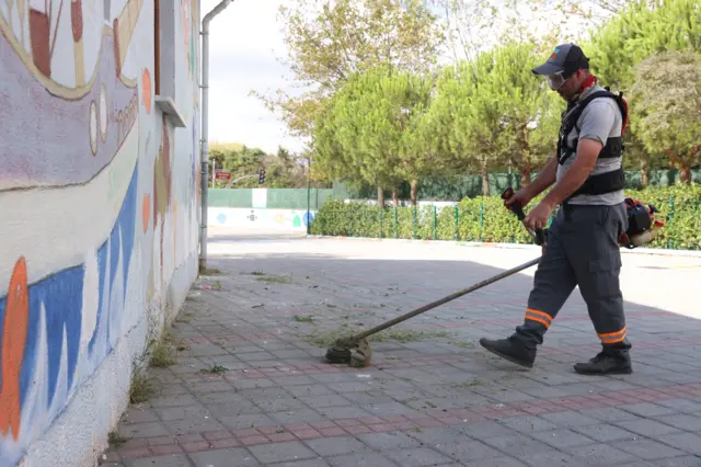 Temizlik görevlisi okul bahçesini süpürüyor. 