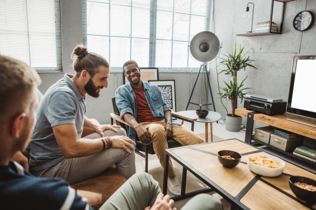 Homens sentados em sofá conversando e rindo