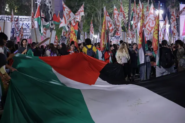 Kalabalık flamalar taşıyor, ellerinde dev bir Filistin bayrağı var