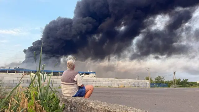 Чоловік дивиться, як горить завод