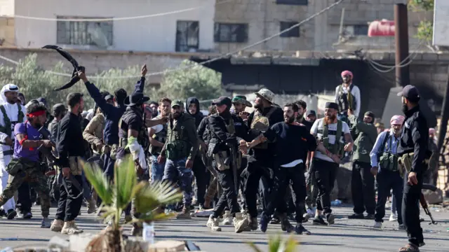 ضباط من قوى الأمن الداخلي يرافقون سجيناً درزياً ويمنعونه من التعرض لهجوم من قبل البدو، عند نقطة تفتيش تابعة لقوى الأمن الداخلي تعمل على منع مقاتلي البدو من التقدم باتجاه السويداء، 19 يوليو/تموز 2025.