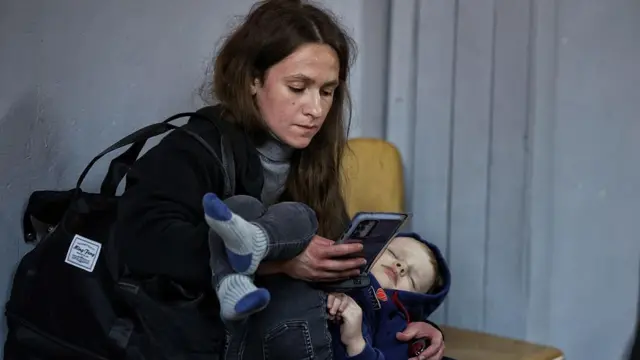 Młoda matka z małym dzieckiem sprawdzająca telefon
