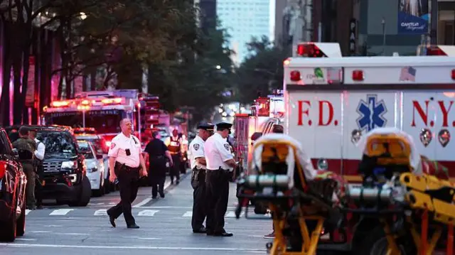Полицейские, машины экстренных служб вдоль обочины дороги, на заднем плане видно высотное здание